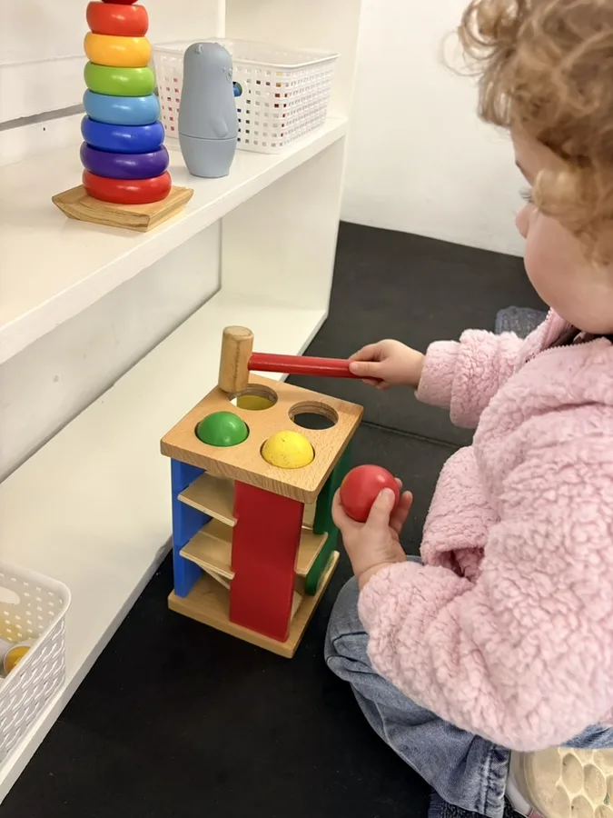 A young child concentrating on a Montessori posting activity