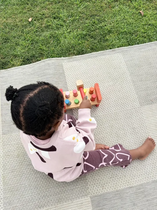A young child using a posting activity outdoors