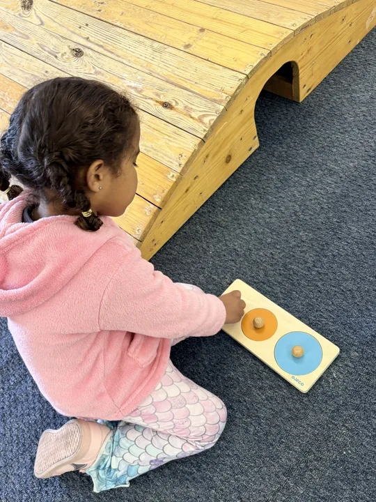 A child concentrating on a Montessori cylinder activity