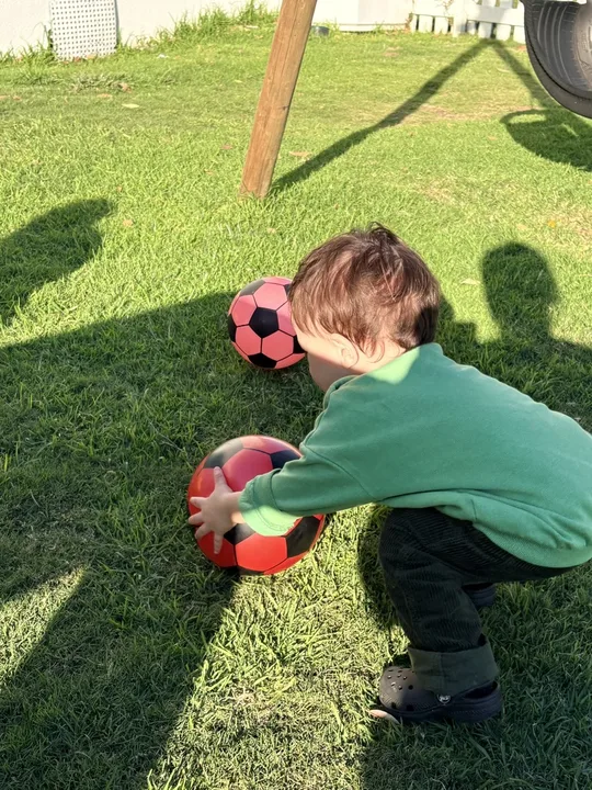A child carrying a ball during outdoor play